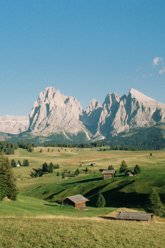 Views of the Sassolungo and Sassopiatto with the Alpe di Siusi plateau and its characteristic wooden houses