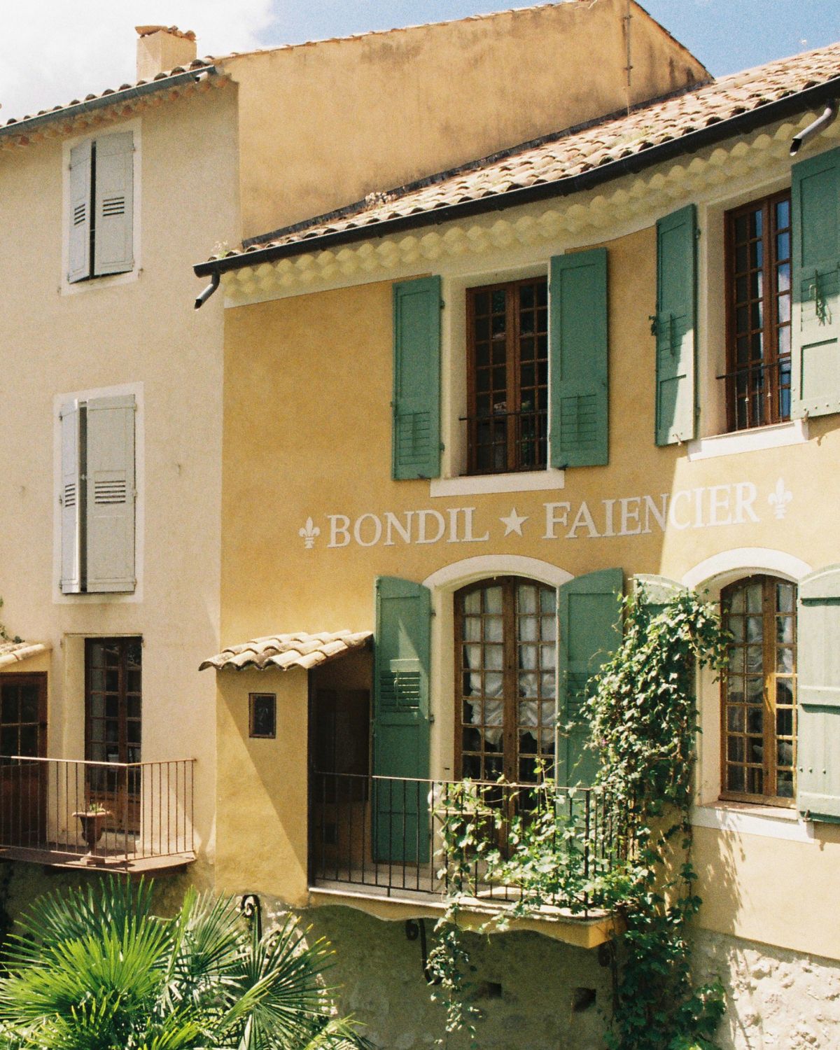 Village of Moustiers-Sainte-Marie, with yellow and green façades. Shuttered windows.