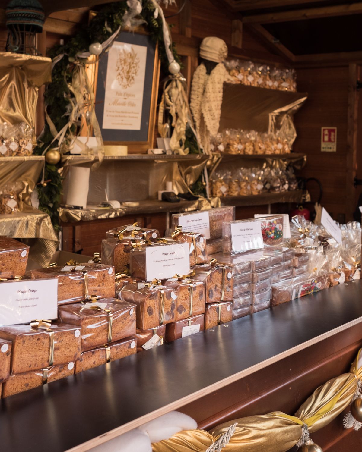 Christmas market wood stand with plastic wrapped cakes and cookies.
