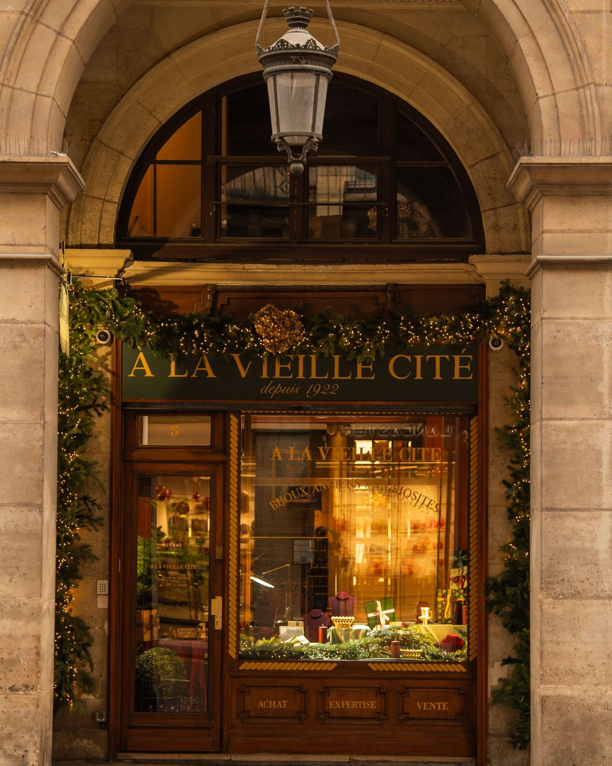 Classic wooden door with Christmas adornments, under an archway of a classic building in Paris.