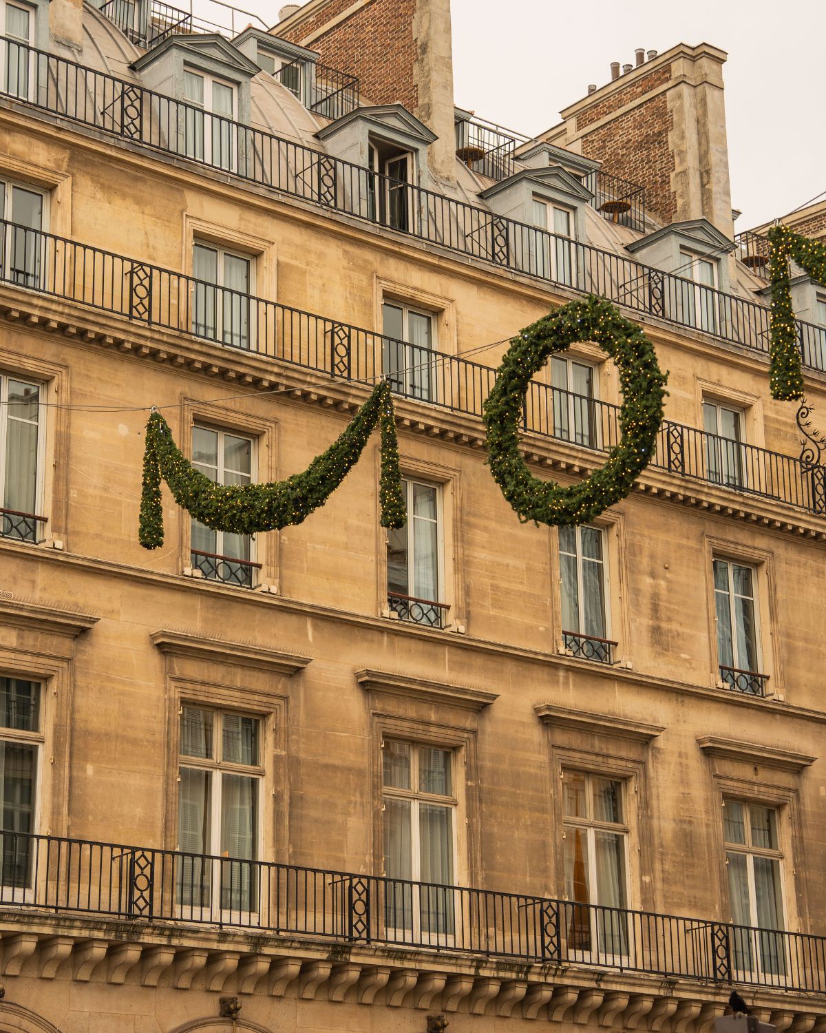 Classic building façade in Paris, with Christmas ornaments hanging in the street.