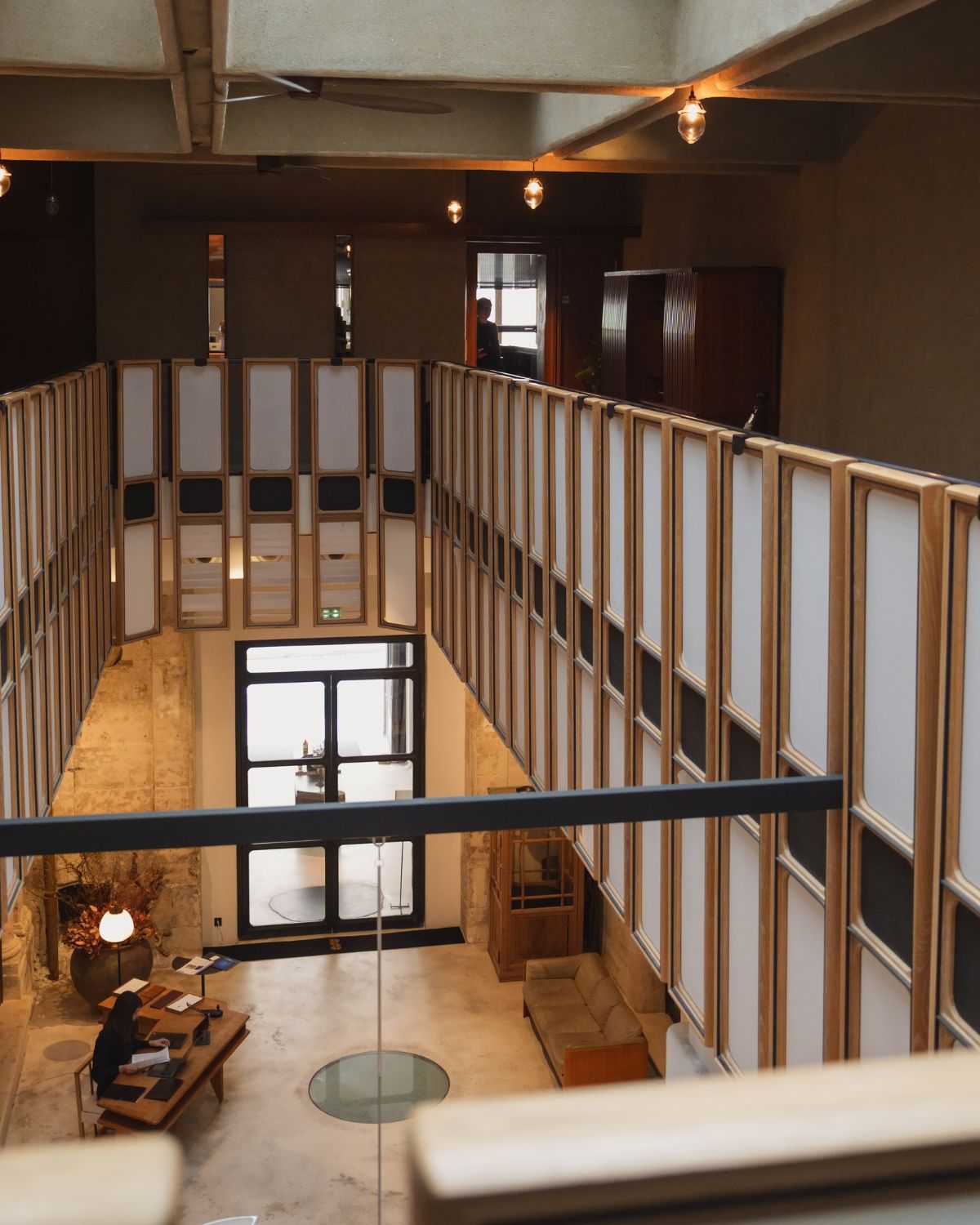 A tea room interior setting, with wood panels, a black glass door, stone walls and wood furniture.