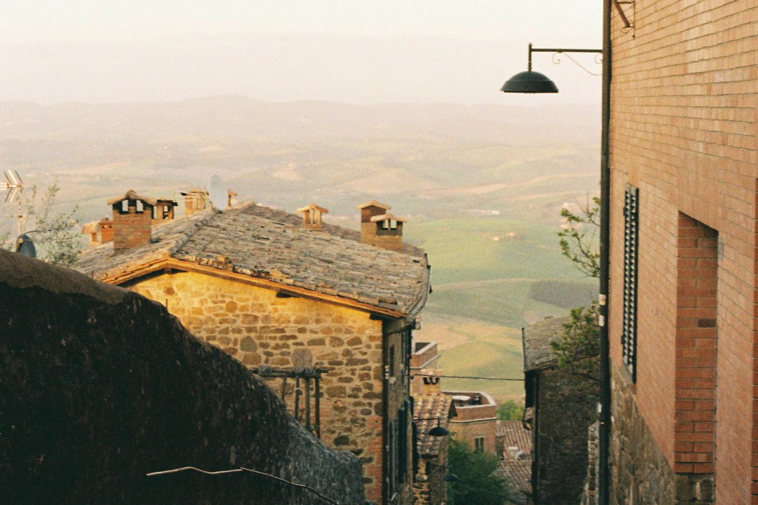 Cobbled stone houses, sitting on a hill, with valleys in the background and a golden light shimmering.
