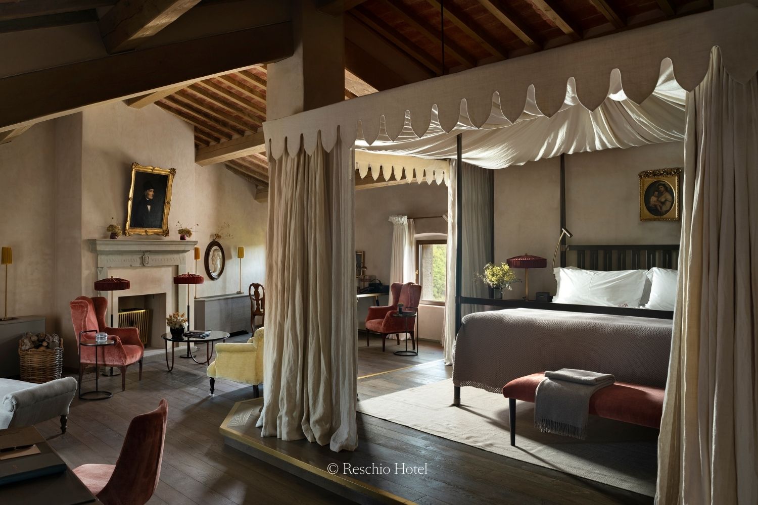 Traditional room, with wooden beam ceilings, red armchairs, gold antique paintings and a dossel white bed.
