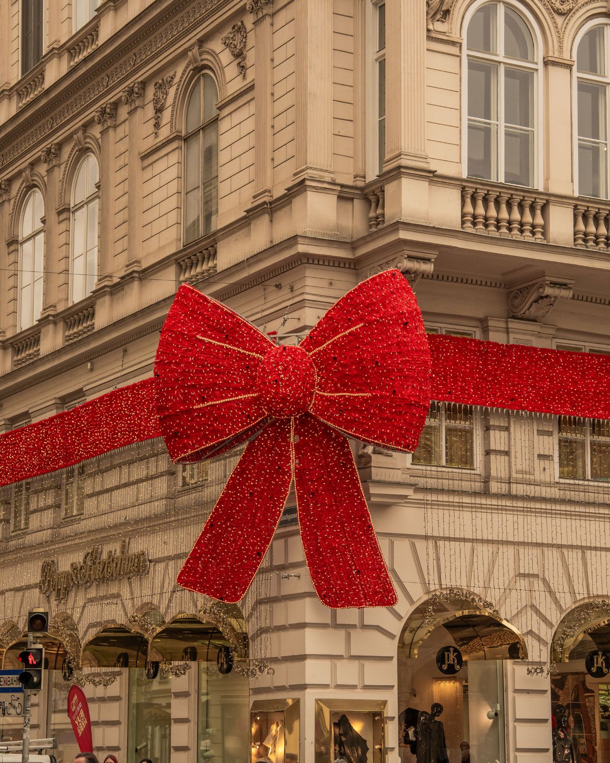 A classic building façade with a largw red sparking Christmas bow.