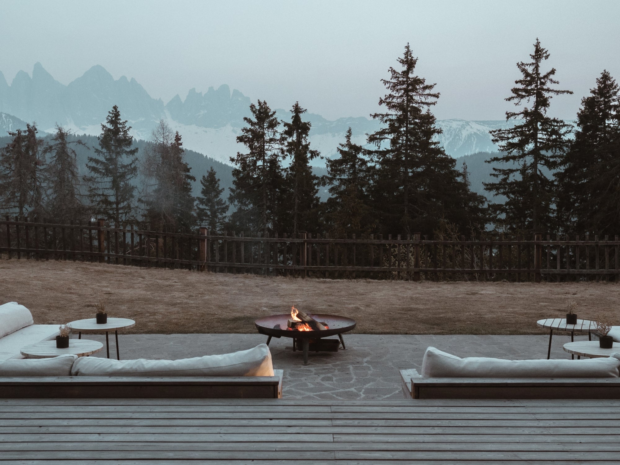 Firepit and outside lounging area with views to the forest and mountains at Forestis Dolomites