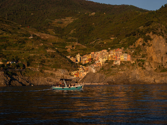The village of Manarola, in Cinque Terre, seen from a boat out on the sea, in the late golden afternoon light.