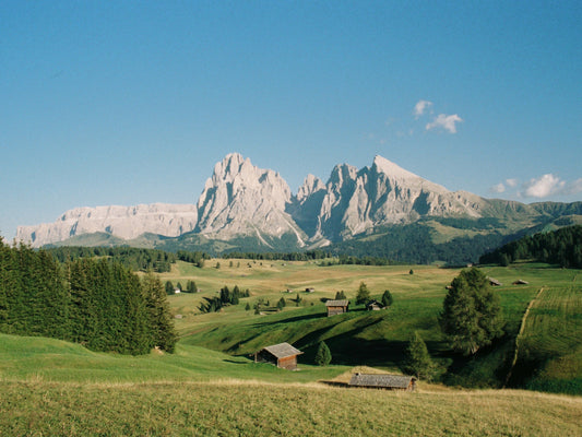 Alpe di Siusi, in the Dolomites, with its traditional wooden alpine huts, and the rough peaks at far