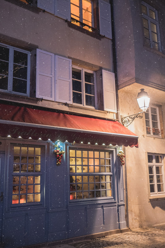 The façade of a cosy restaurant on a snowy december evening in Strasbourg, Aslace