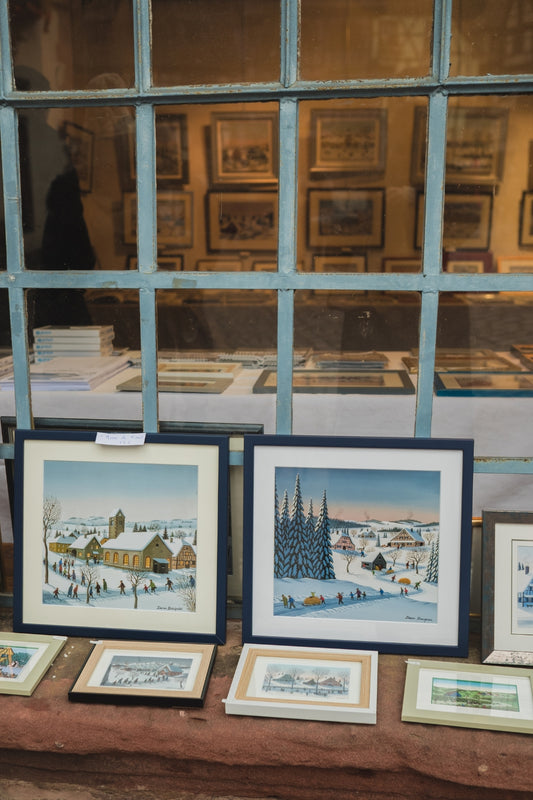 Framed paintings of Alsatian winter landscapes on display in the store of artist Dennis Bauquier, in Kaysersberg