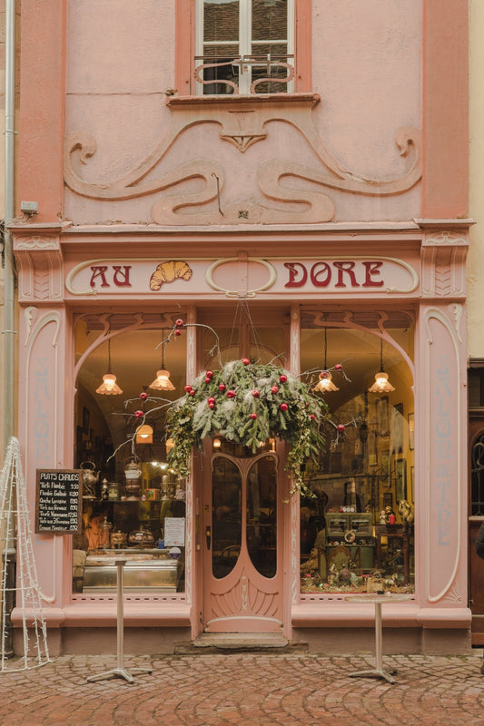 The pink façade of the café Au Croissant Doré, in Dolmar, decorated for Christmas