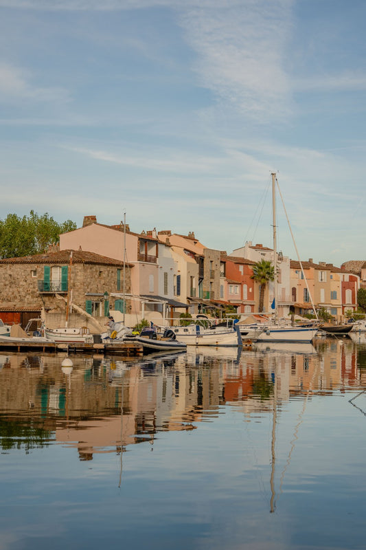 The calm waters of the canals of Port Grimaud, in the French Riviera, perfectly mirroring the houses and the yachts on a late afternoon