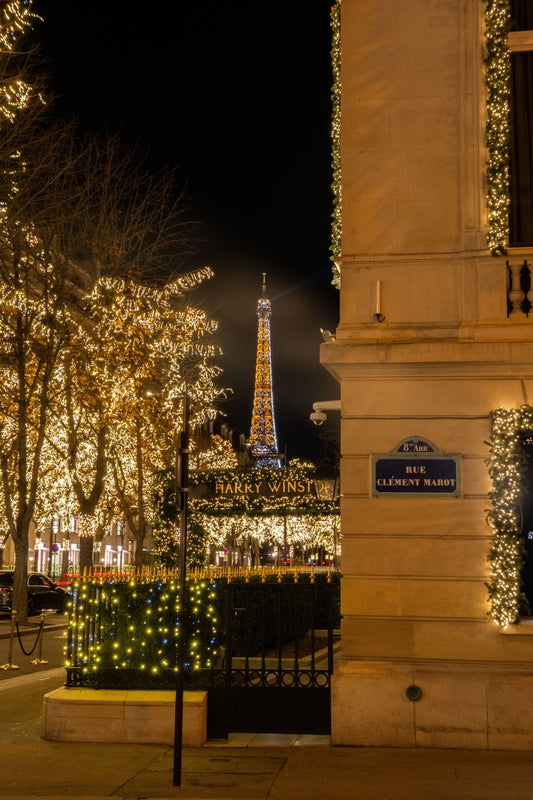 The Eiffel Tower fully illuminated and sparkling seen from the fully decorated Avenue Montaigne, in Paris