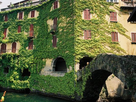 The Devil's Bridge in Nesso, surrounded by ivy-covered pastel-toned buildings, in Lake Como