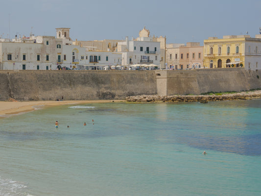 The pastel toned town of Gallipoli, in Puglia, Italy, built on top of the stone walls overlooking the clear waters beach