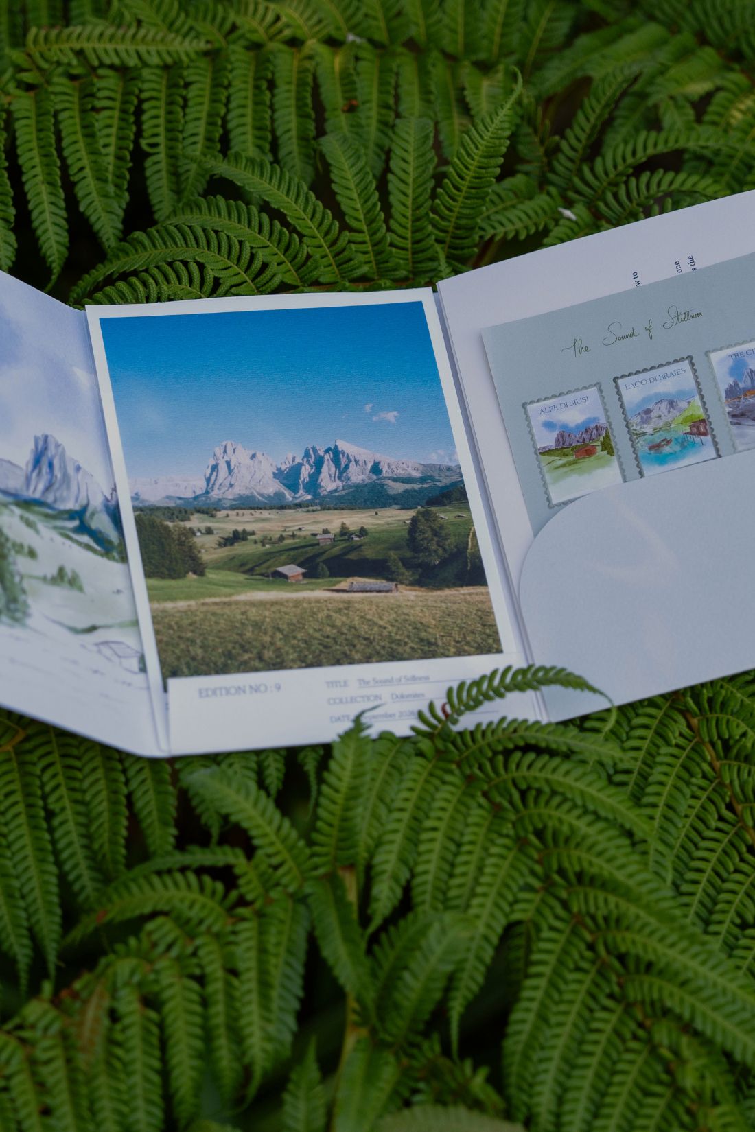 The open fold-out from the September 2026 'Dolomites' edition of Simply Slow Mail, by Simply Slow Traveler, where the illustration on the interior of the fold-out, as well as one of the postcards and the sticker sheet can be seen