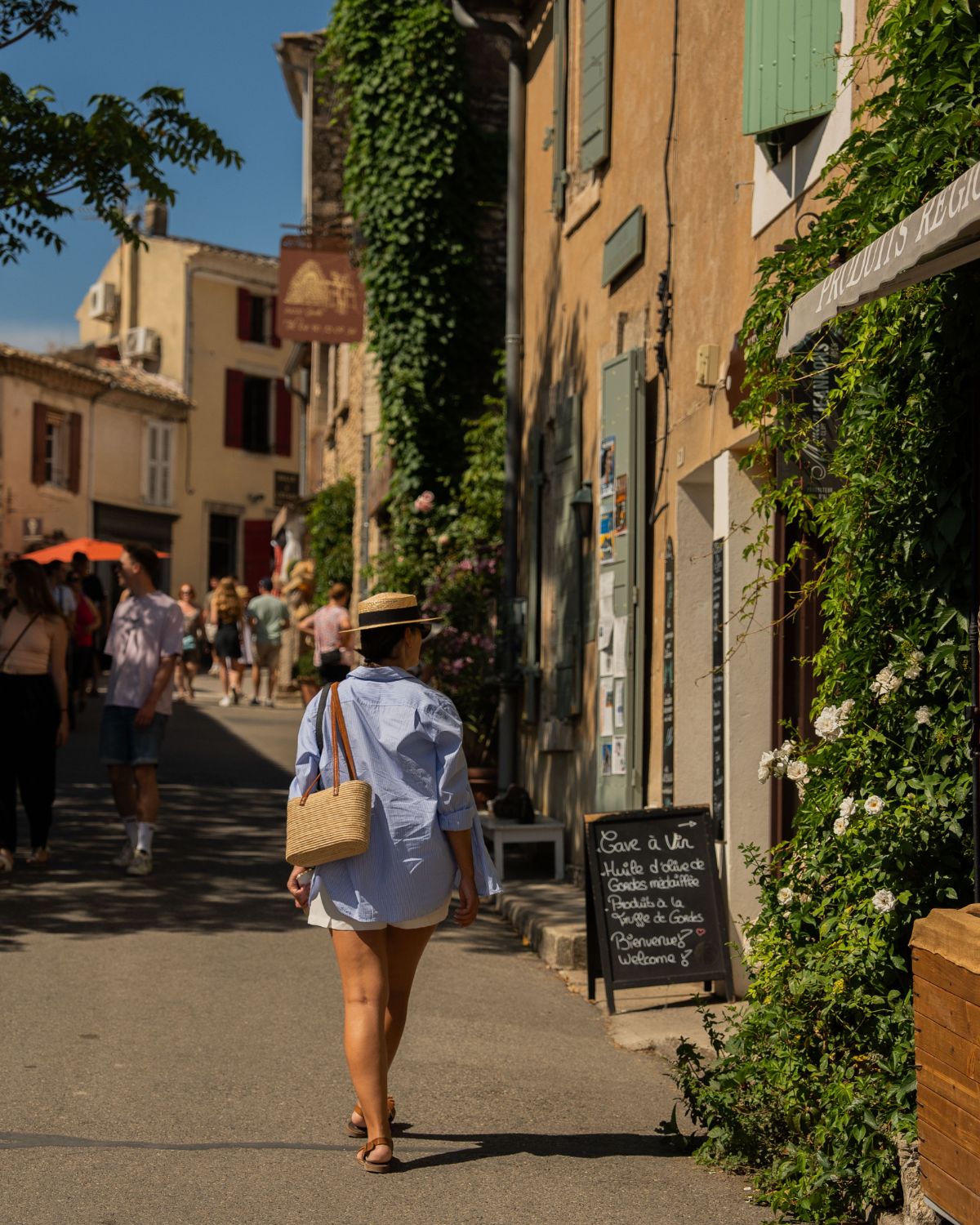 Woman in blue shirt, walking in picturesque village.
