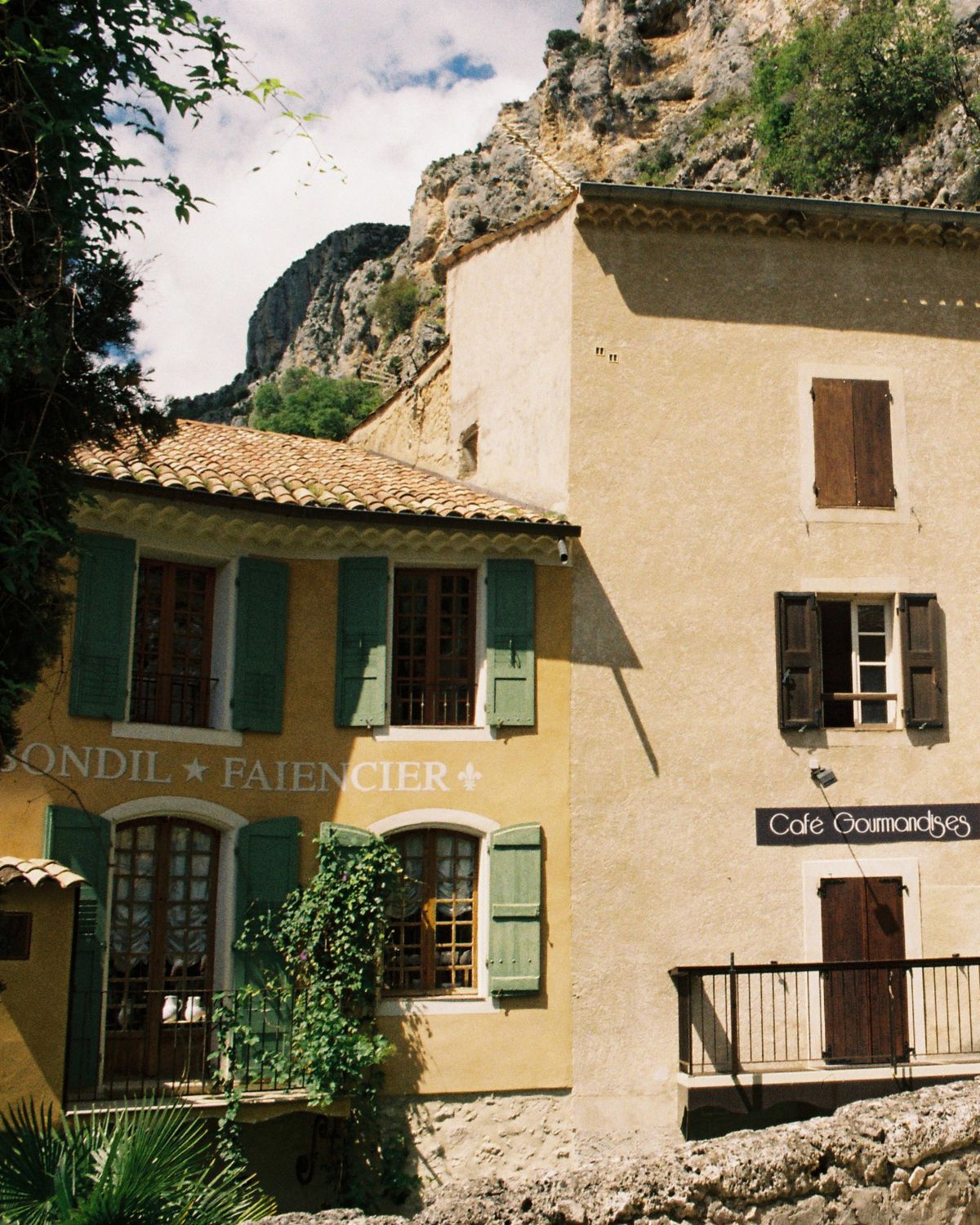 Village of Moustiers-Sainte-Marie, with yellow and green façades. Shuttered windows.