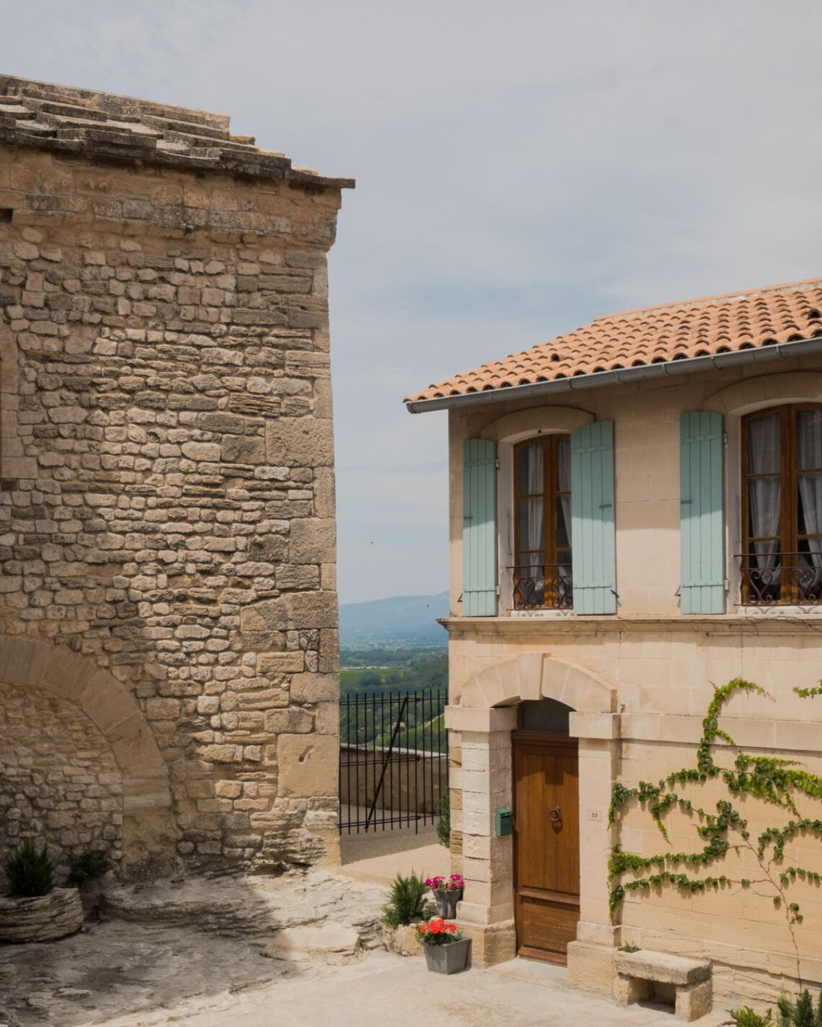 Hilltop house in Venasque. Shuttered windows, cobblestone streets, soft pastel tones and climbing plants.