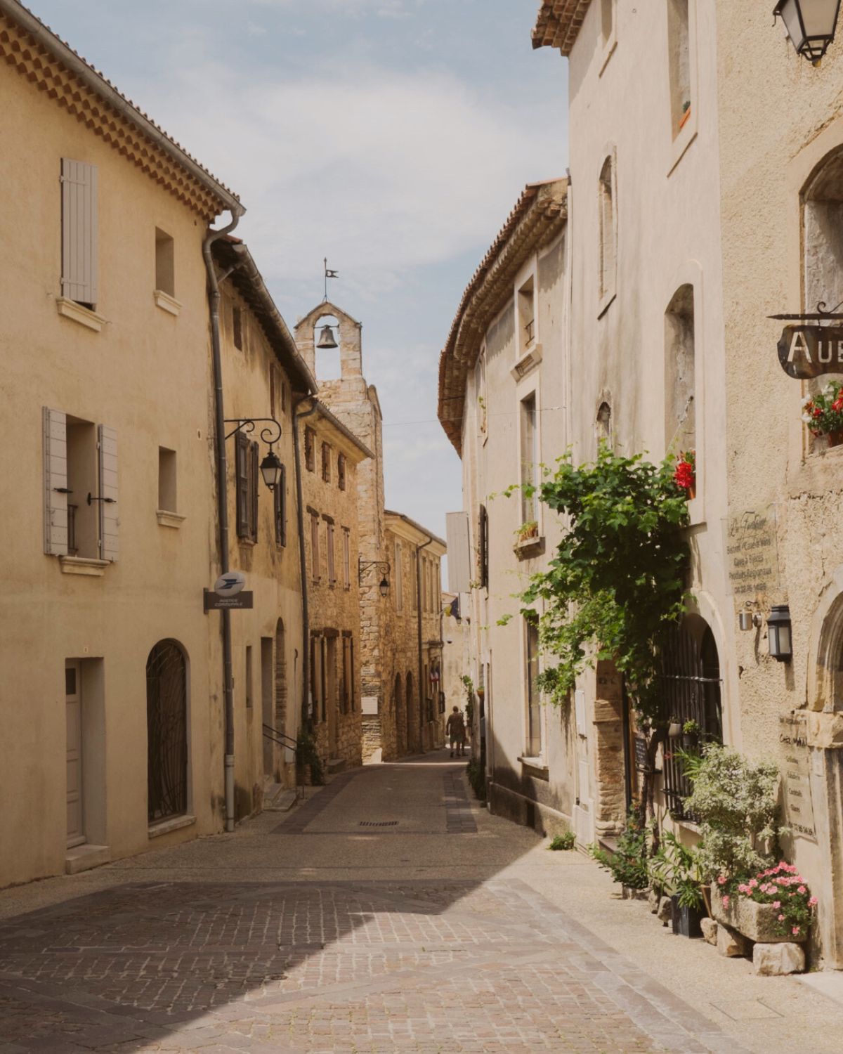 Cobbled stone street, with flowers and a church bell.