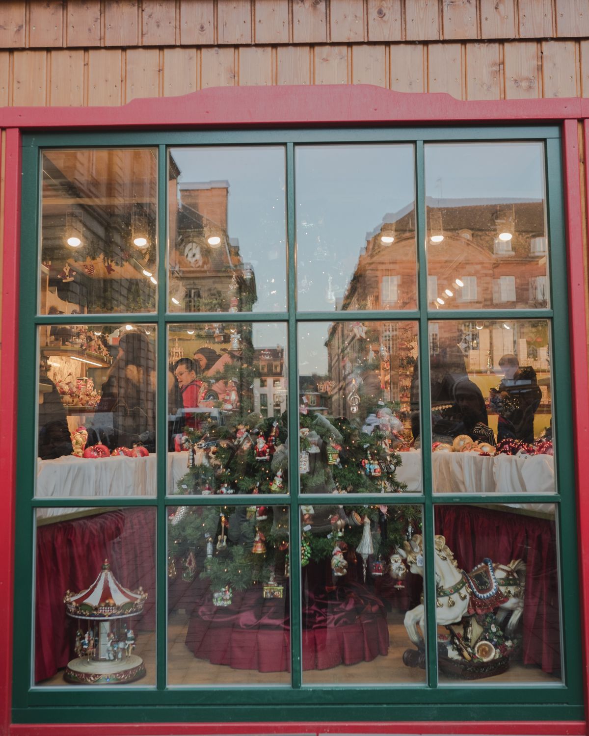 A green window of a store, with a Christmas tree and adornments on the inside.