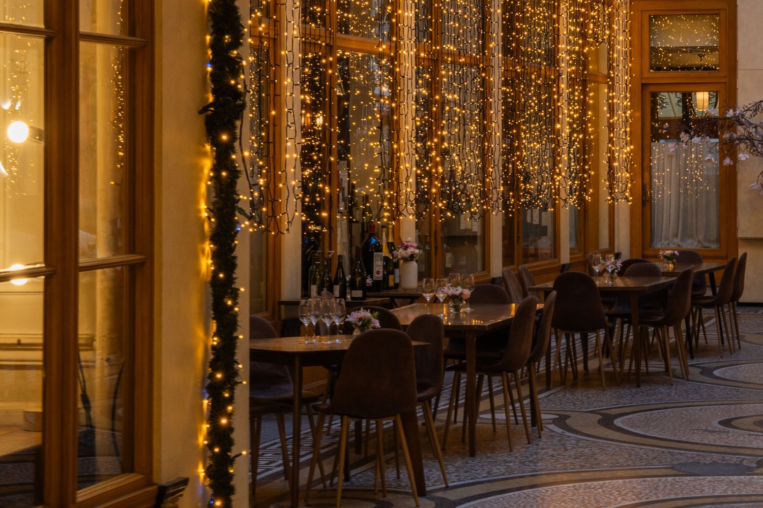 Coffee setting with brown chairs and tables, next to windows with Christmas lights.