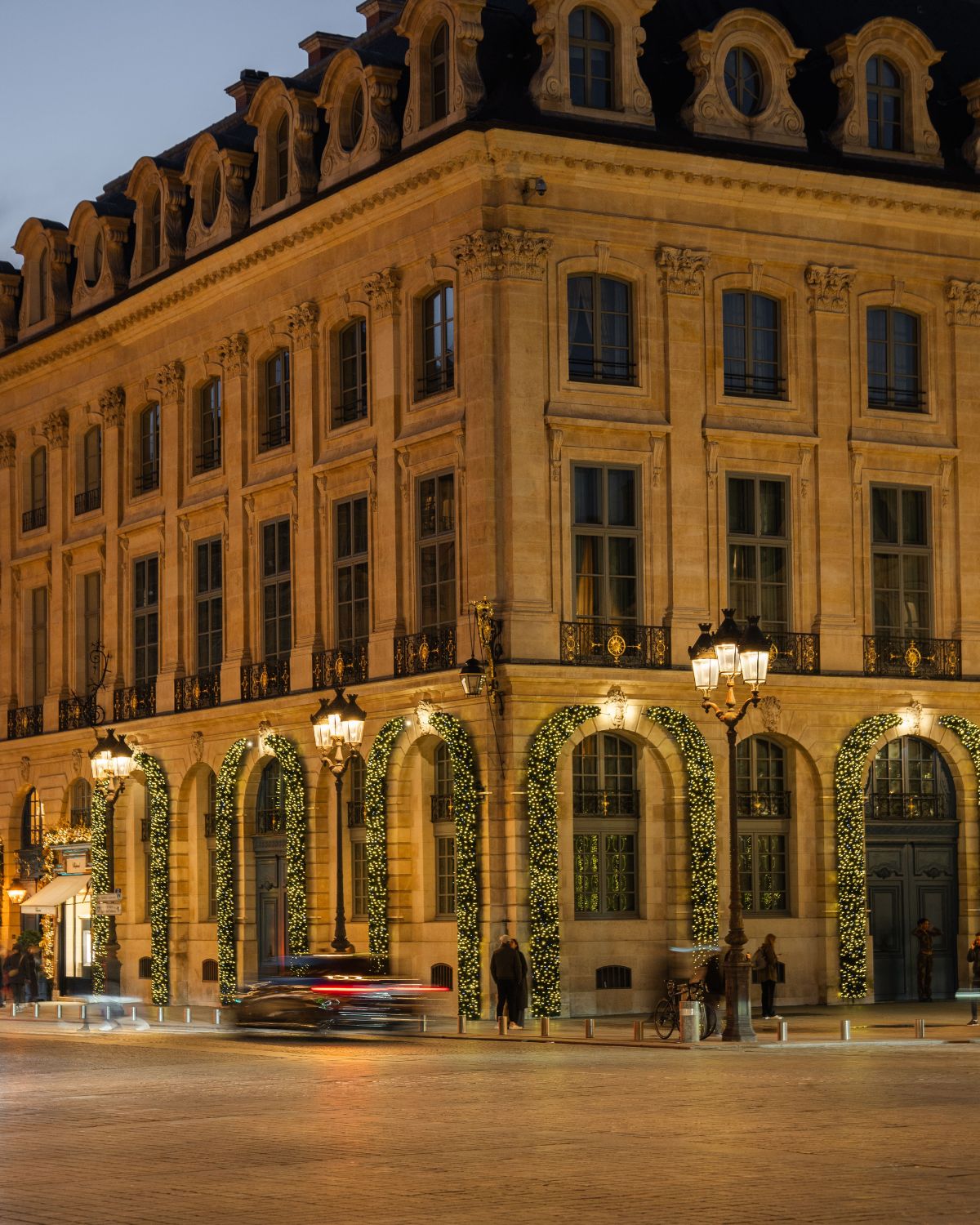 Classic building with antique outdoor high black lamps and Christmas adornments with lights around the windows and doors.