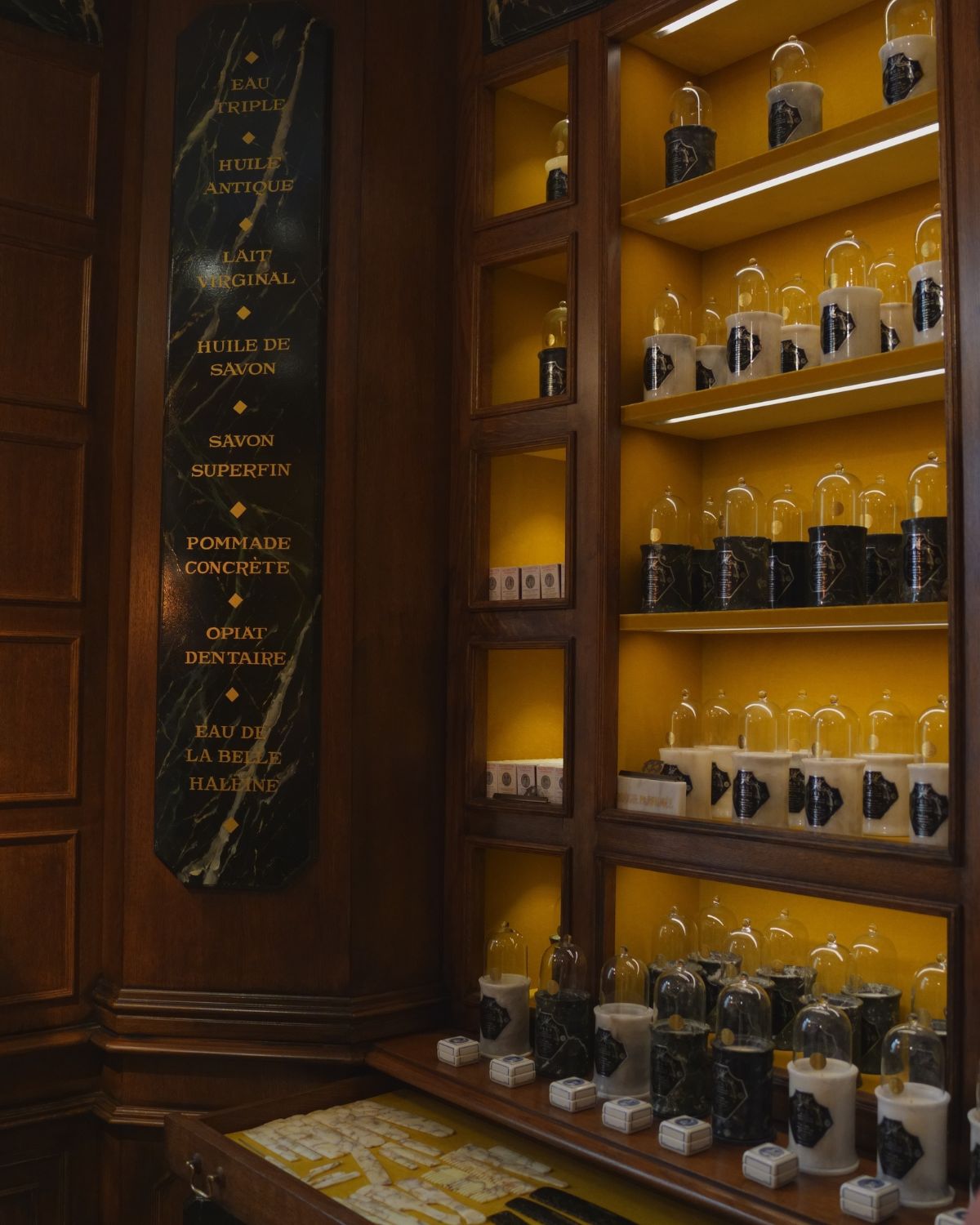 Glass covers and stone pots on wooden shelves, with velvet yellow interiors.