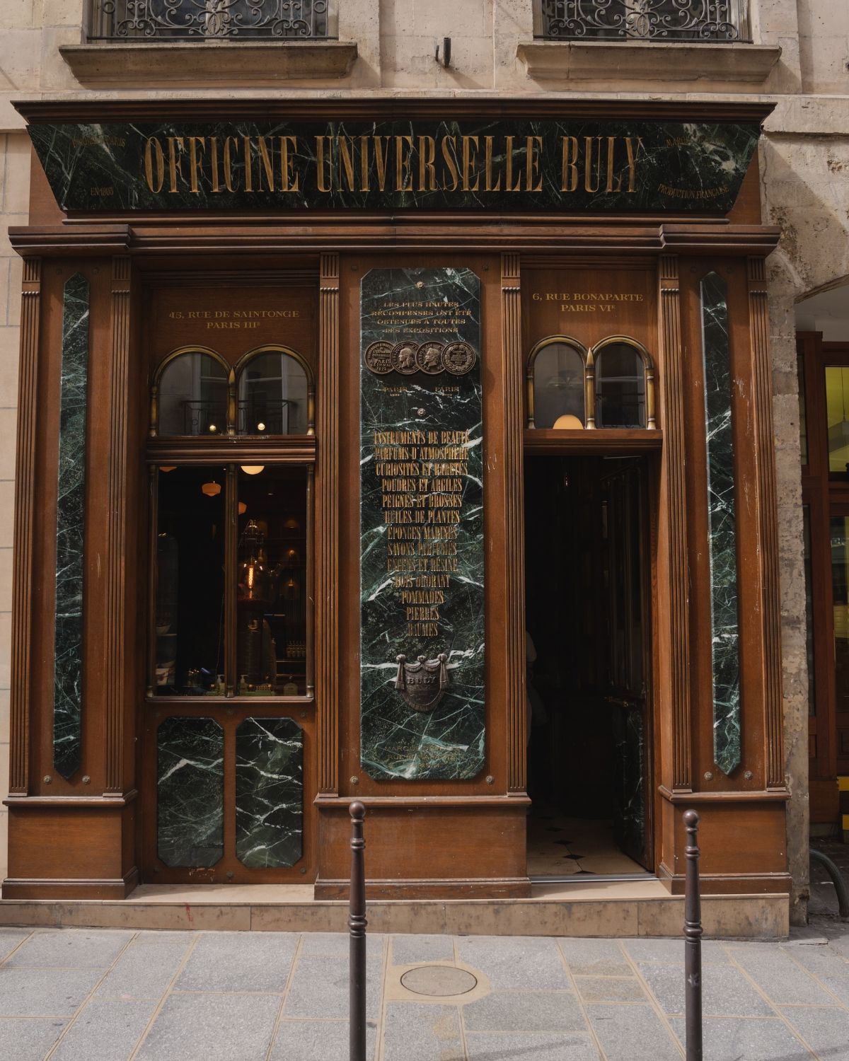 A store's façade, with wooden panels and rims, and a green stone paneling.