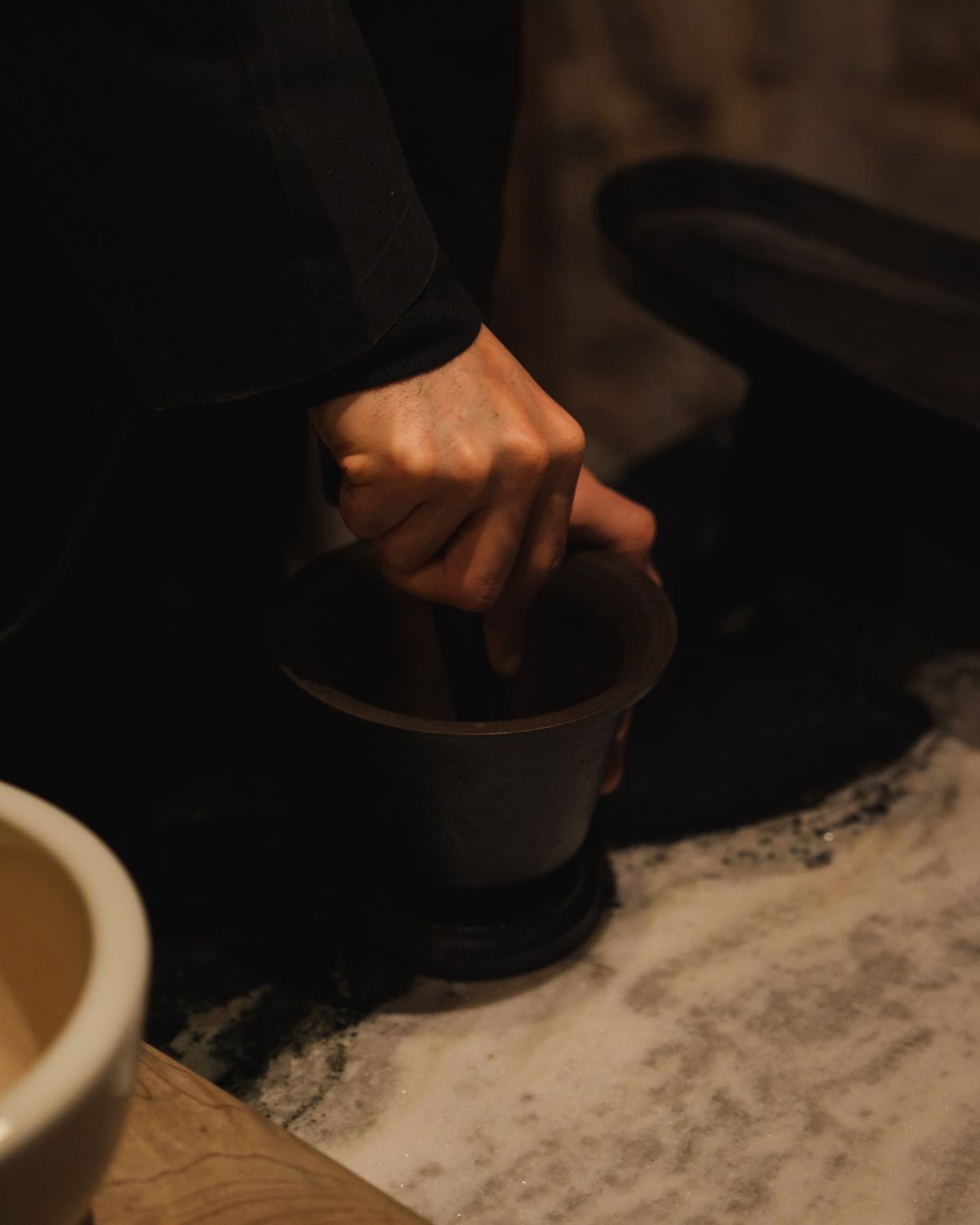 A hand pressing tea on a black base, on top of a stone counter.