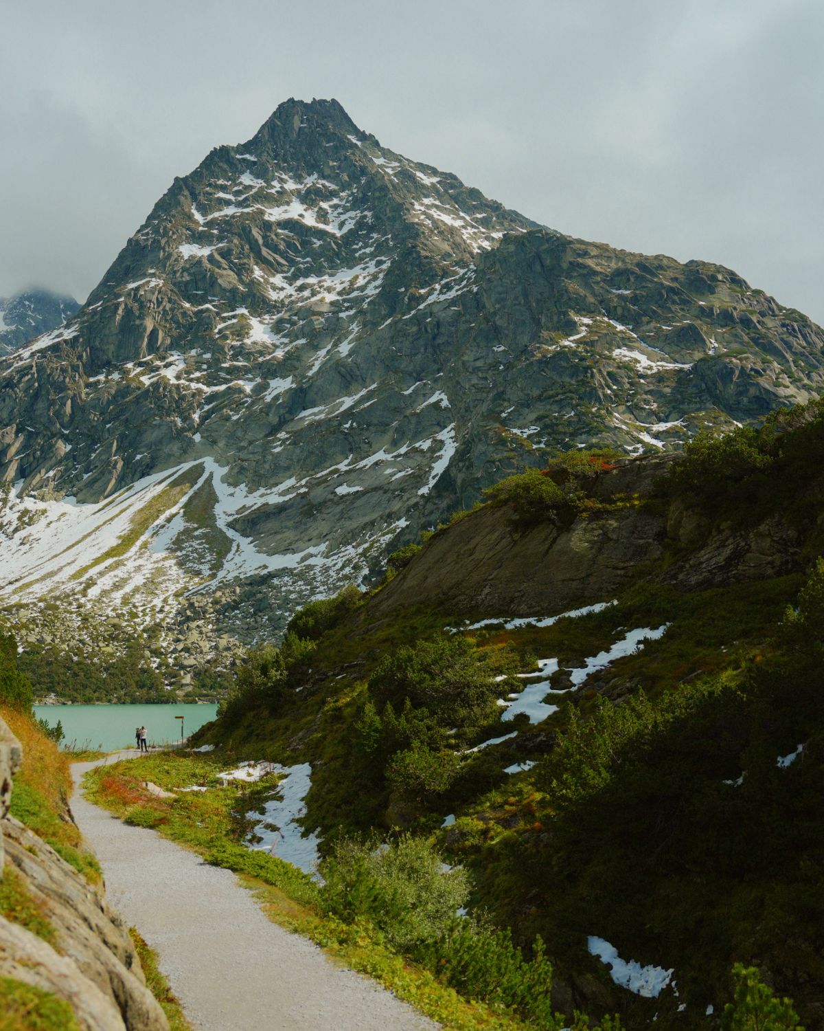 Turquoise lake, next to a rocky and snowy mountain.