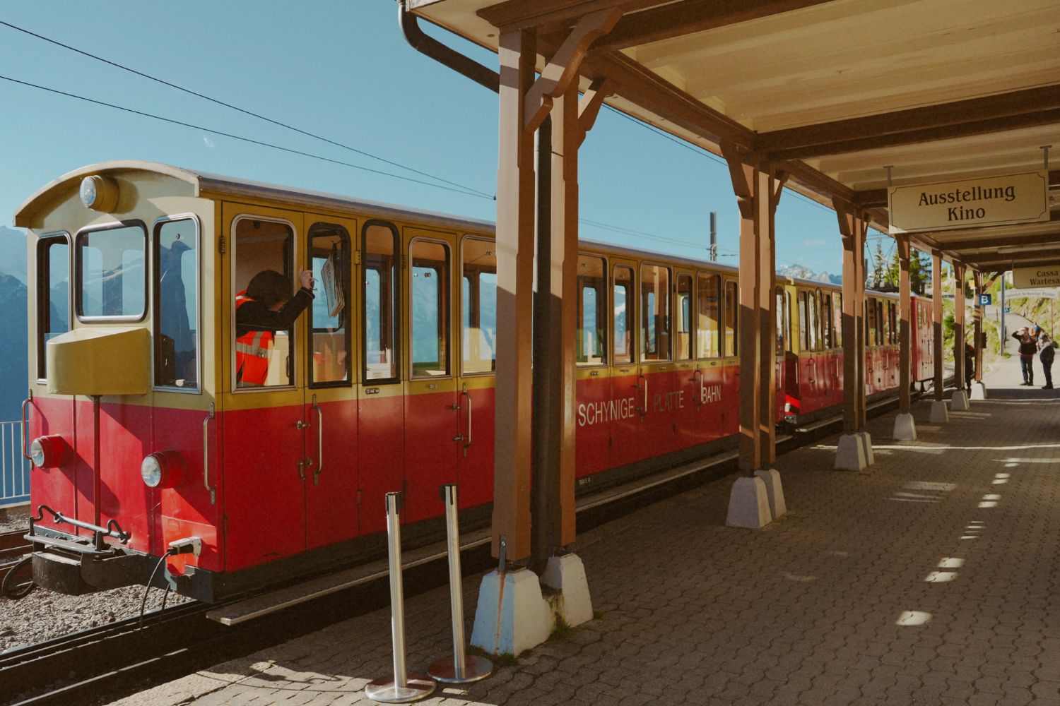 A red and yellow train leaving the station of Ausstellung Kino.
