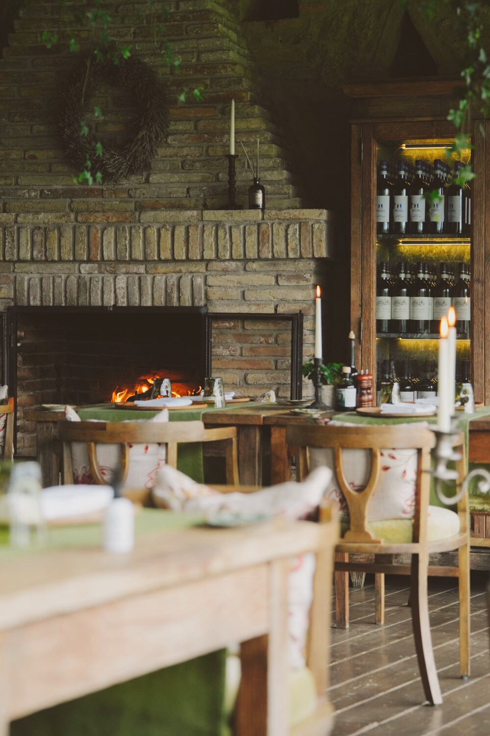 A charming restaurant interior, with a fireplace, a wine wooden storage and furniture.