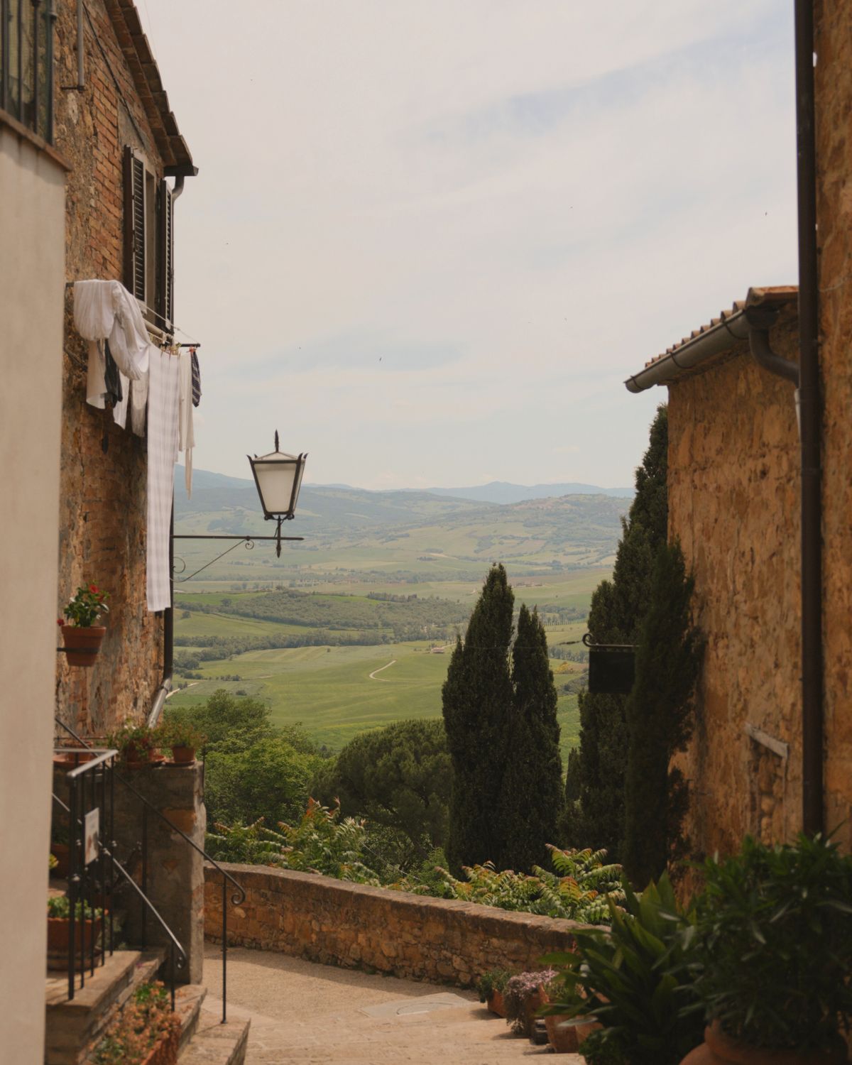 Cobbled stone houses, sitting on a hill, with valleys in the background.