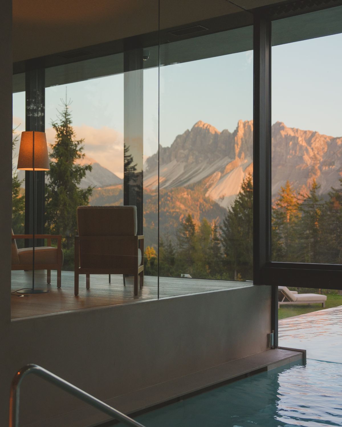 Glass windows, an indoor/outdoor pool and two armchairs overlooking mountains.
