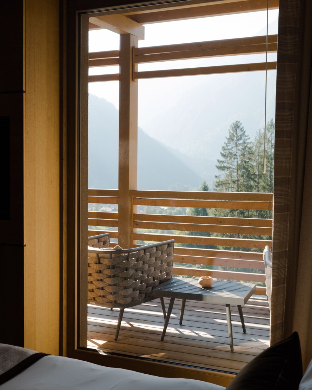 A wooden deck with outdoor furniture, overlooking the mountains and high trees.