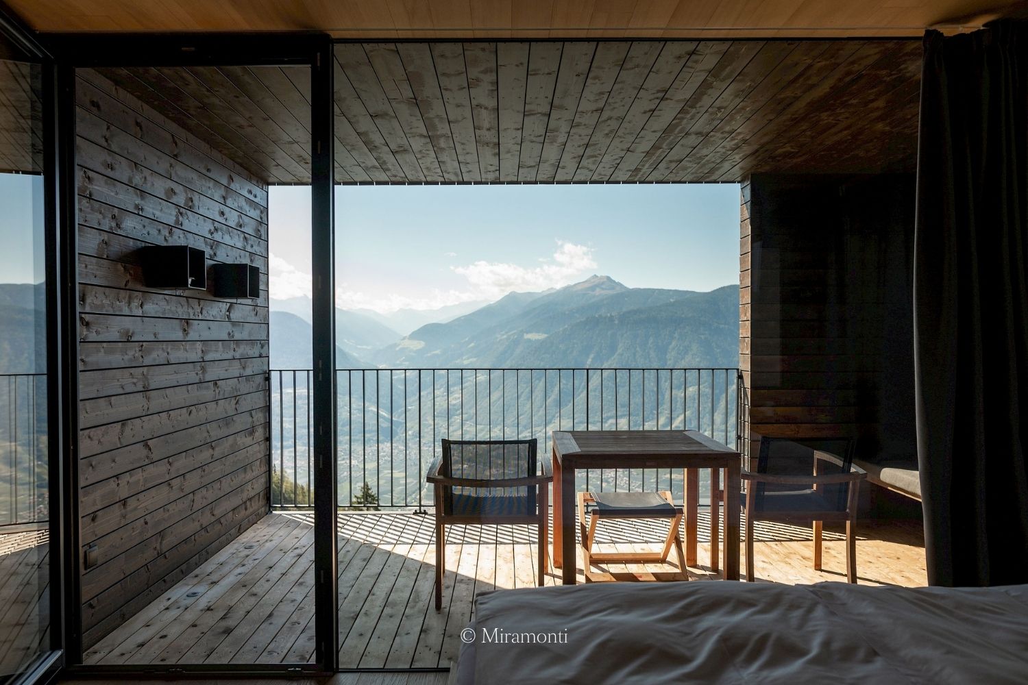 Hotel wooden balcony, with outdoor furniture overlooking the green mountains.