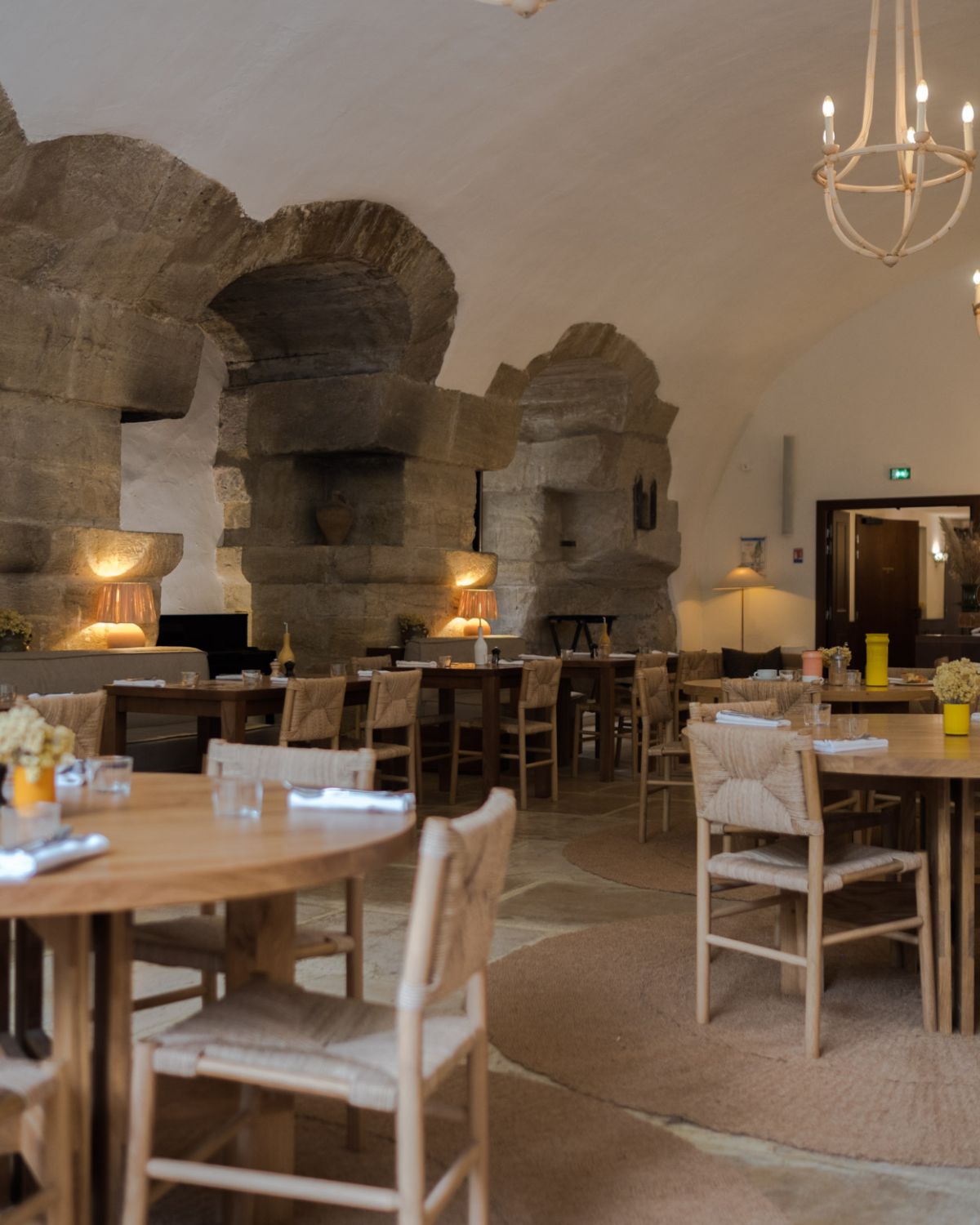 Stone wall and floor, interior restaurant setting, with light wood furniture.